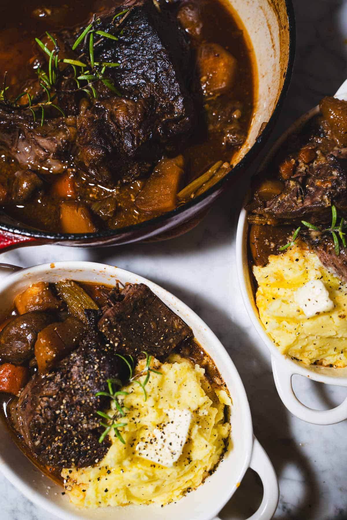 the best tender 2 lb pot roast for two in a dutch oven and served in two white oval deep sided dishes over mashed potatoes.