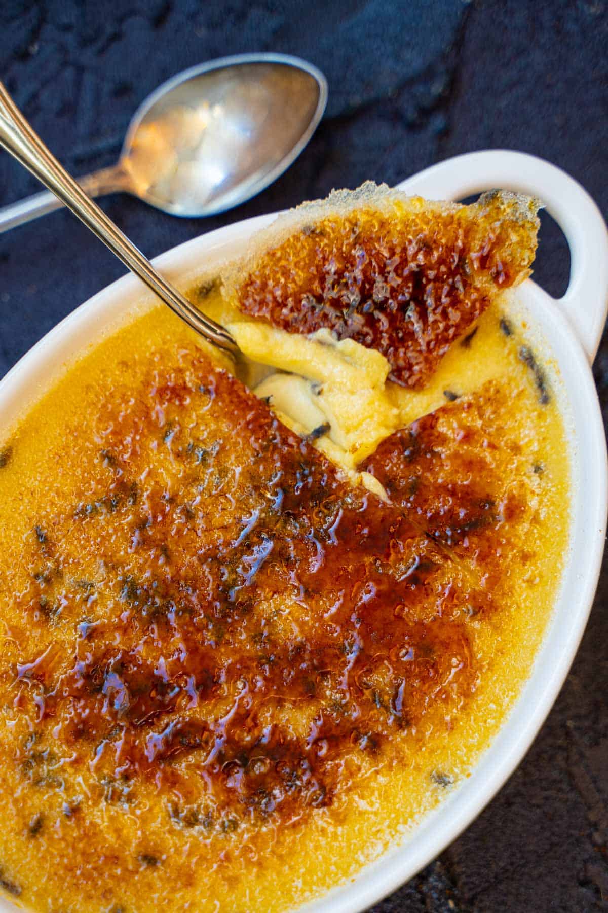 Easy creme brulee recipe for 2 with a spoon cracking into the caramelized sugar topping.