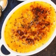 Easy Creme Brulee recipe for 2 + flavor variations in a ramekin on a wood table.
