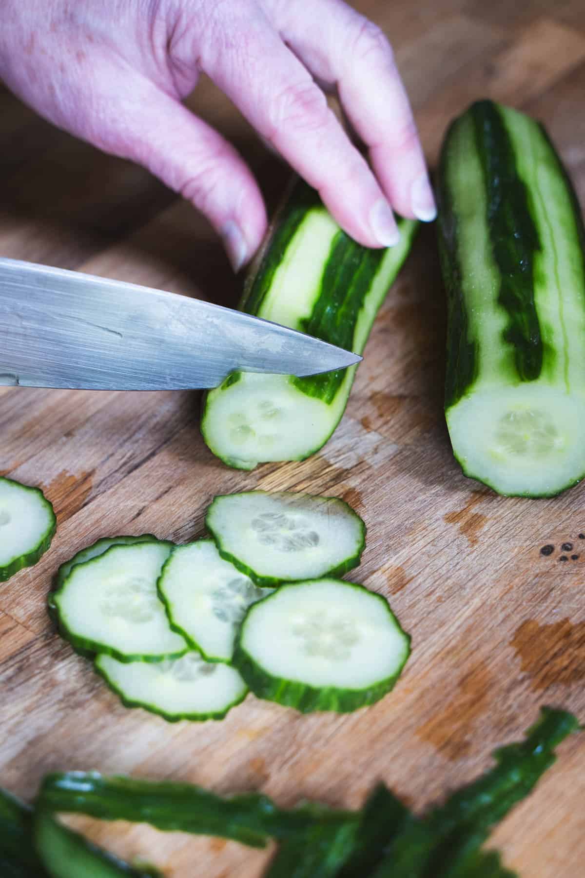 Slicing english cucumber with a chef's knife for easy swedish quick pickled cucumbers.