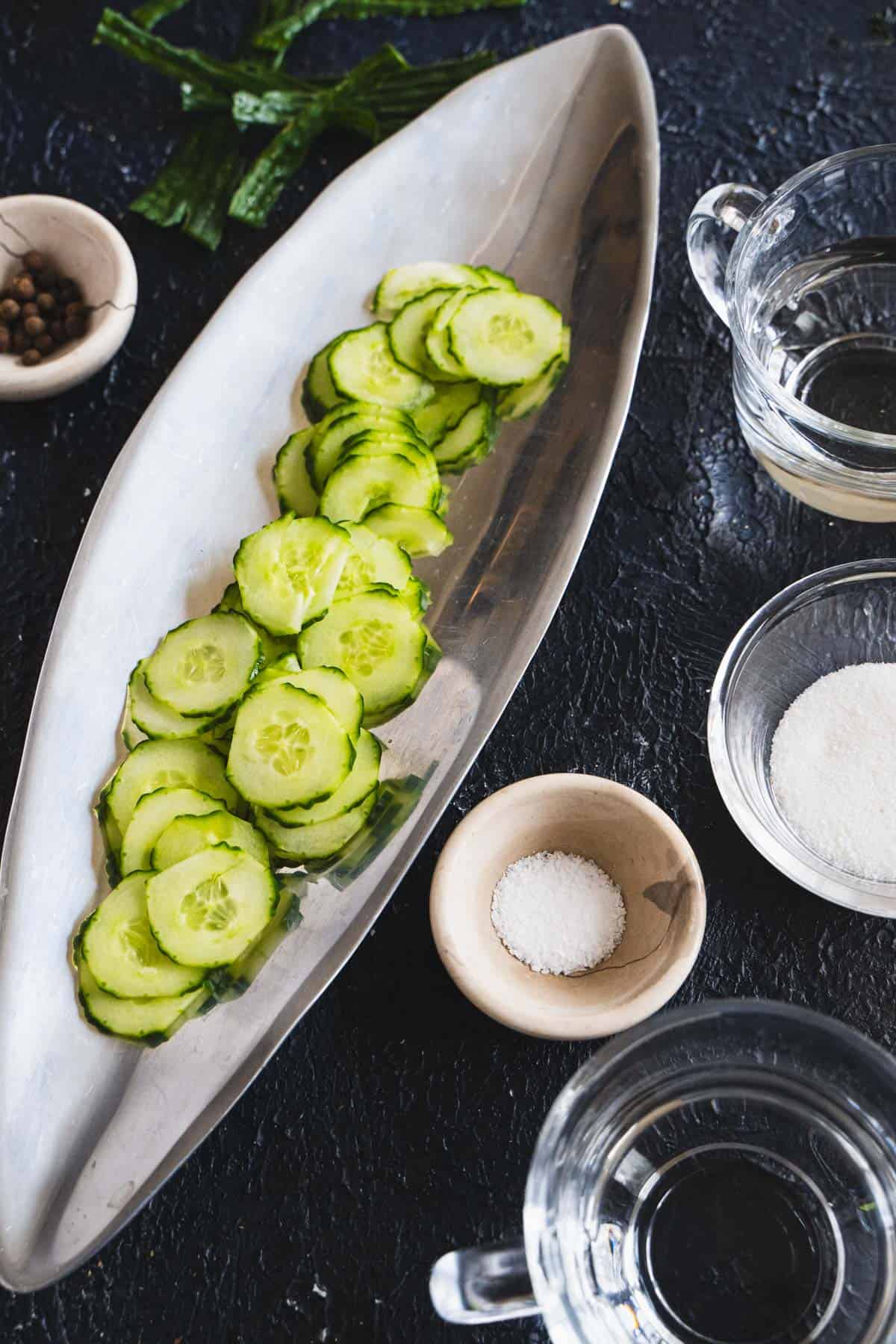 Easy Swedish pickled cucumbers ingredients in ingredient bowls on a dark table.