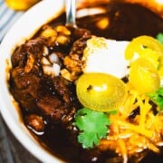 Easy Pork Chili Colorado Recipe no tomatoes in a white soup bowl served with cornbread on the side.