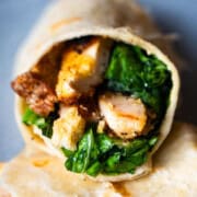 Crispy Panko Chicken Caesar Wrap cut open sitting on top of an uncut wrap on a blue plate.