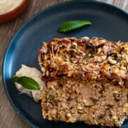 Two slices of Lamb meatloaf on a blue plate the rest in the loaf pan served alongside hot honey yogurt.