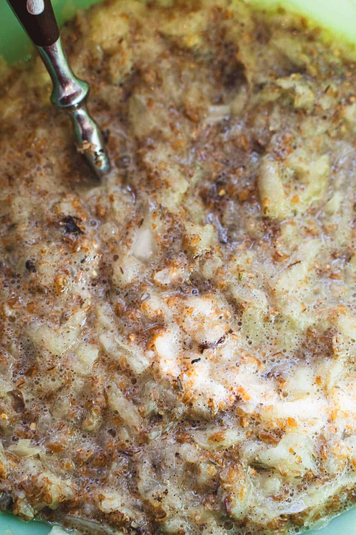 Bulgar bloomed to make 1 lb lamb and ground beef meatloaf recipe for two in a green bowl with a spoon.