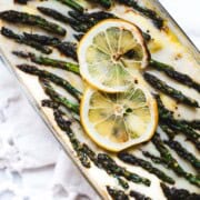 Lazy ravioli lasagna with white sauce and asparagus tips and lemon slices garnish.
