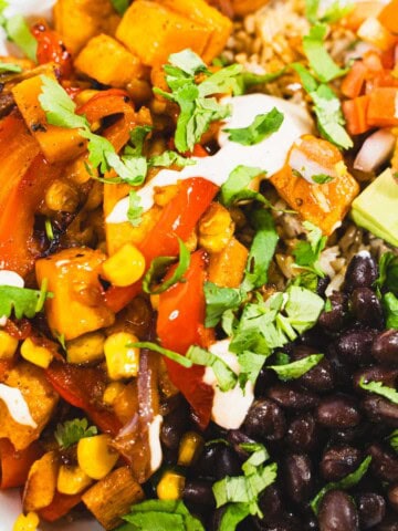 Roasted vegetable fajita bowl topped with avocado, salsa and sour cream.