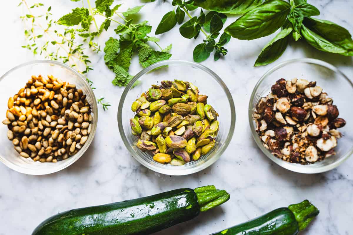 Ingredients sitting in glass bowls on a marble counter to make raw Italian zucchini salad.