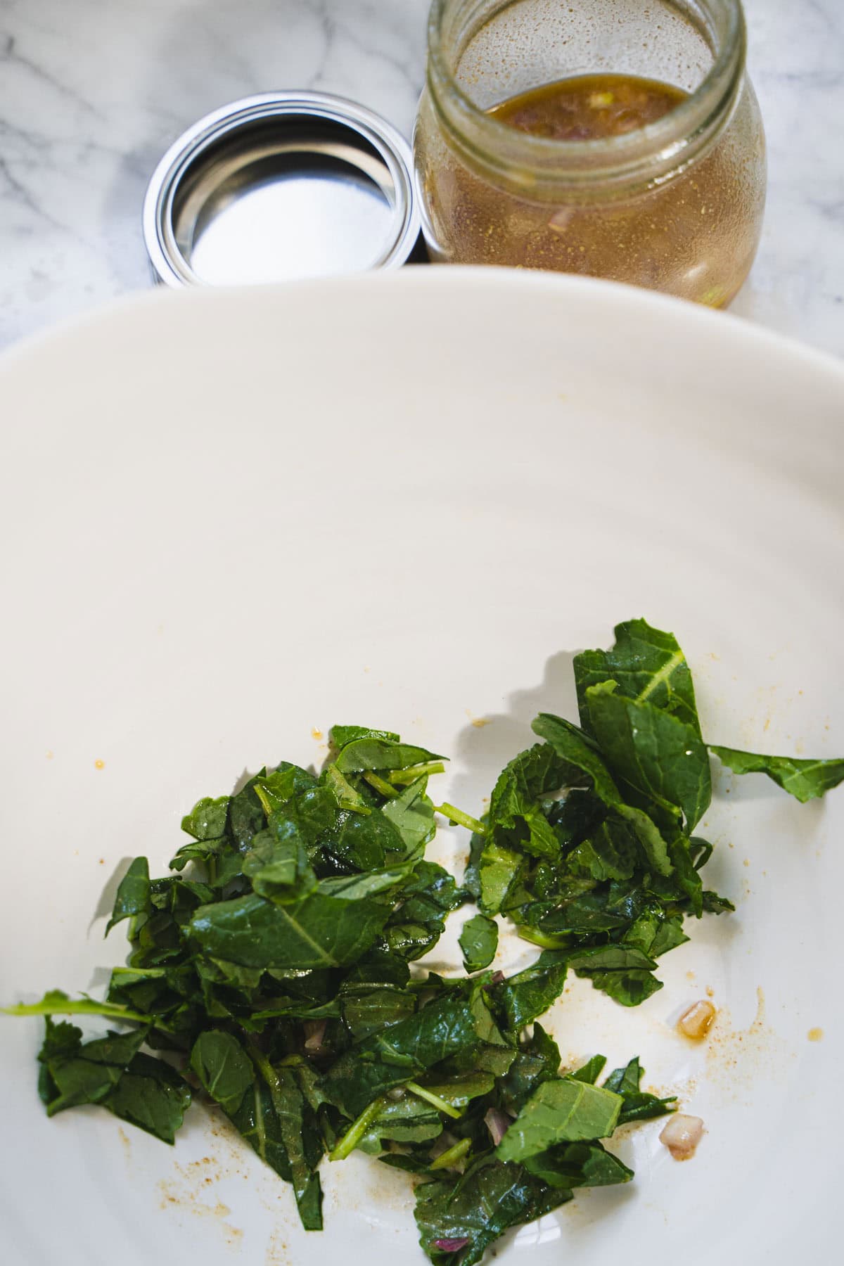 Baby kale dressed with lemon and olive oil in a white salad bowl.