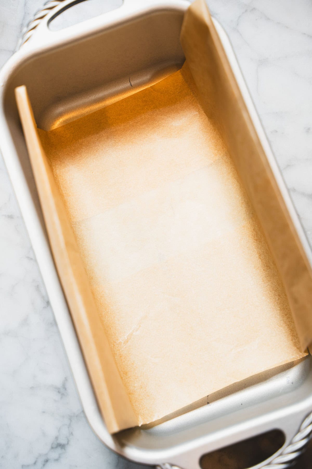 Parchment paper lined loaf pan to make gluten free cinnamon swirl pumpkin zucchini bread.