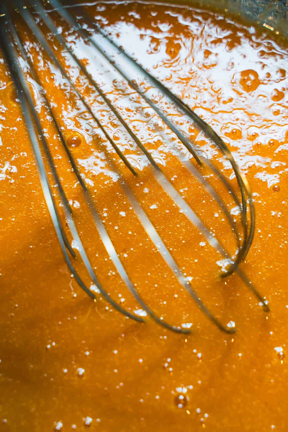 Wet ingredients being whisked by a wire whisk to make gluten free zucchini bread.
