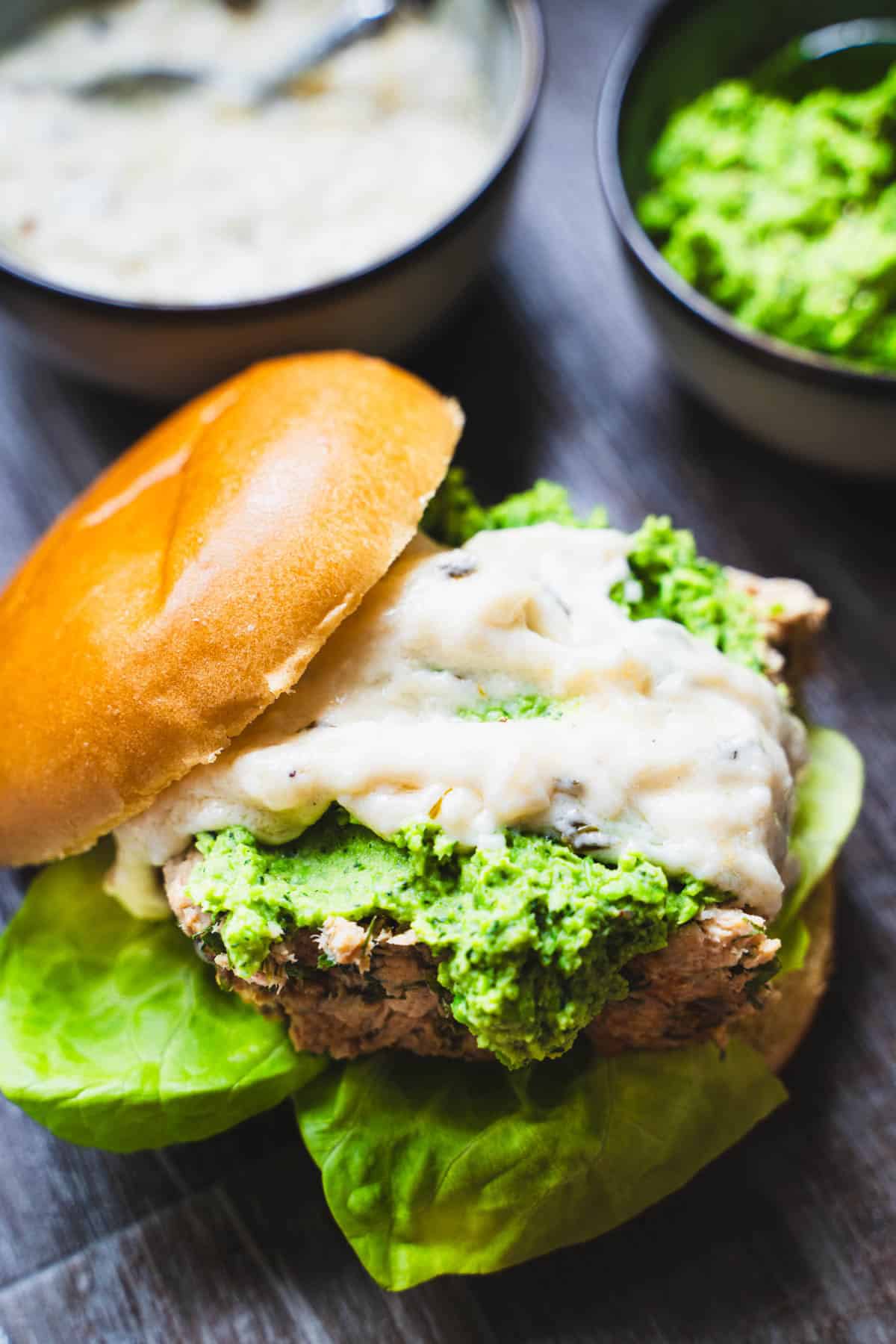 Open face salmon loaf slider on bottom of a bun topped with mint pea puree and champagne sauce