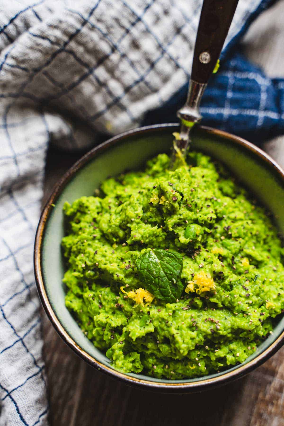 Mint pea puree in a bowl next to a dish towel.