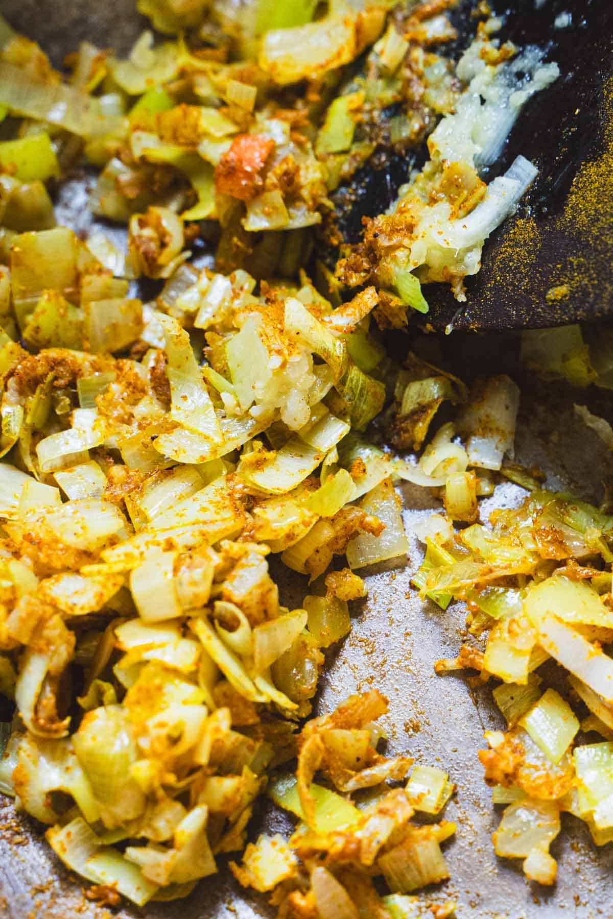Spices added to the leeks and onions in a dutch oven.