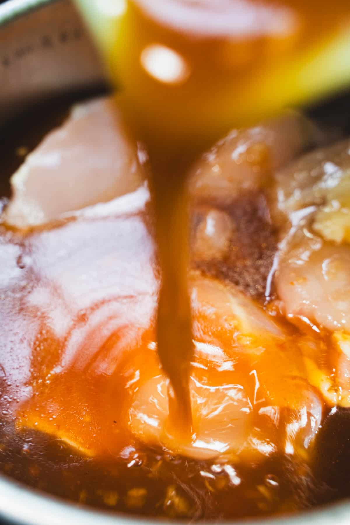 Huli Huli Chicken Sauce being poured over chicken in crockpot.