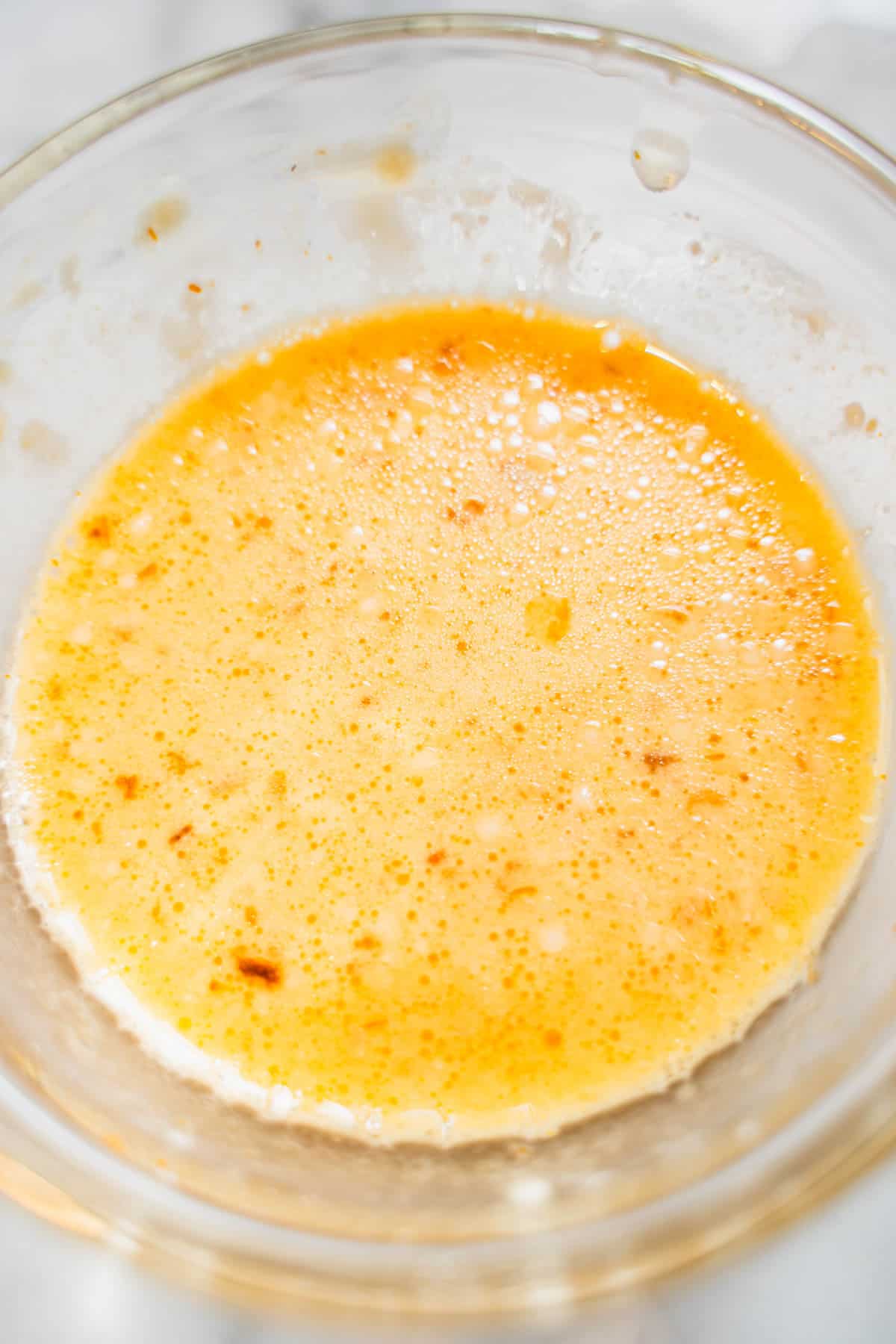 Cornstarch slurry in a small glass bowl on a white counter to thicken the huli huli chicken sauce.