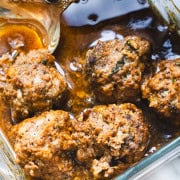 Meatloaf meatballs in black pepper sauce in a glass dish with a silver spoon.