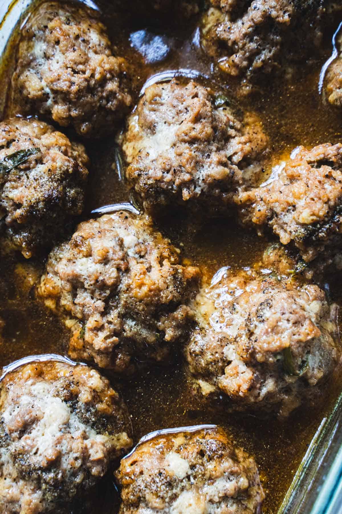 Baked meatloaf meatballs in sauce in a glass baking dish.