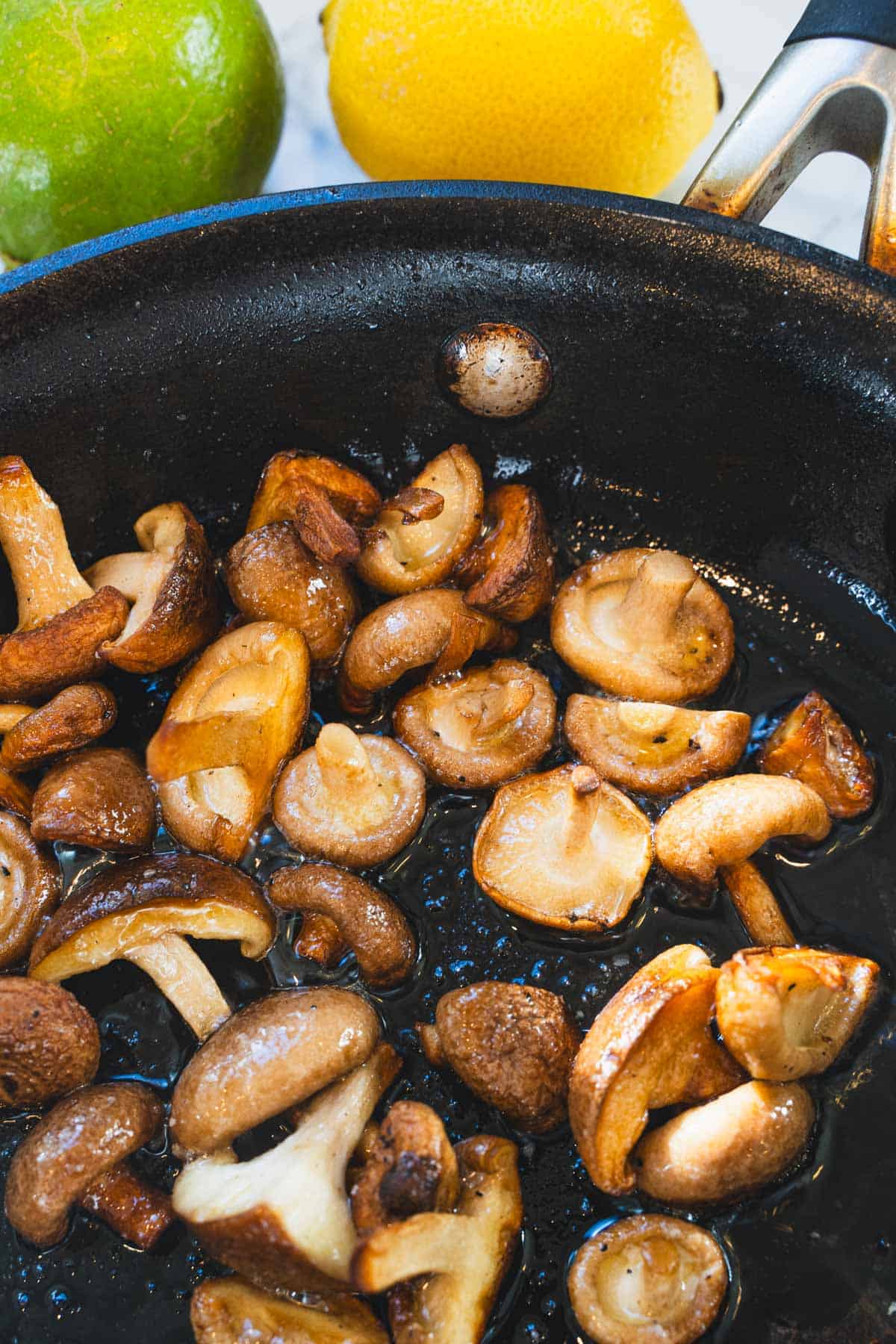 Golden brown mushrooms in a black skillet to garnish the red thai coconut spinach tomato curry soup.