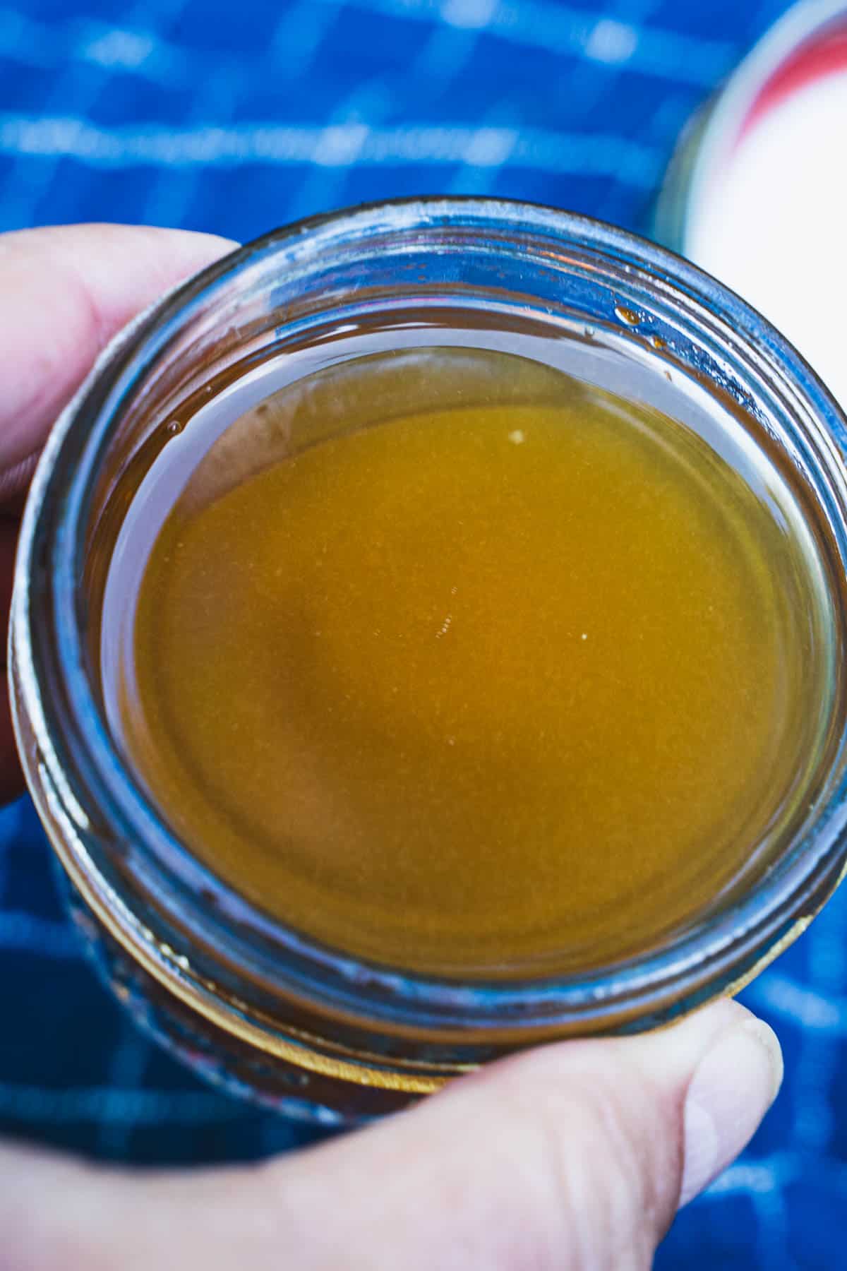 Tomato Essence in a small glass mason jar held in a women's hand.