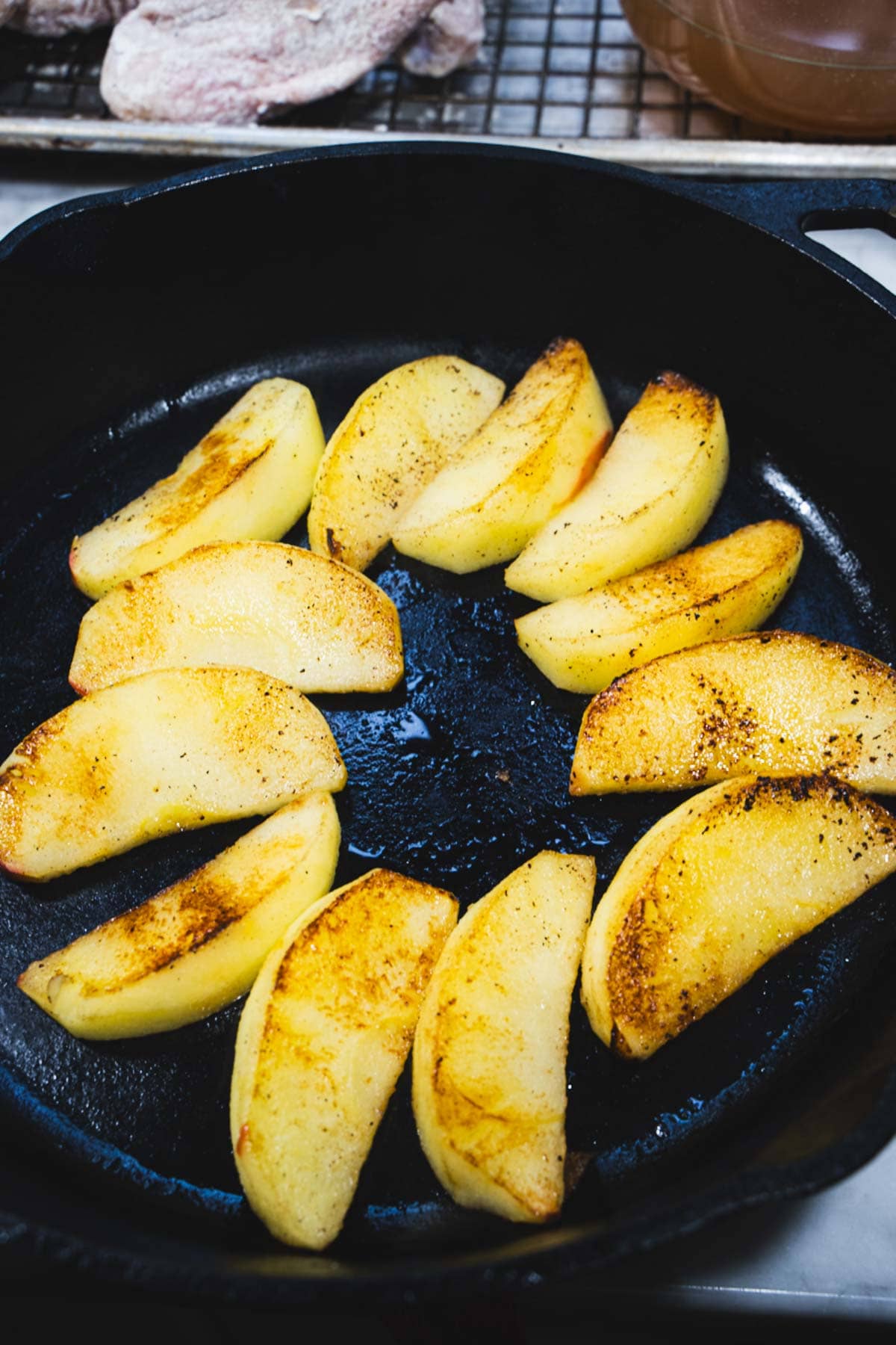 Browned apples for Chicken Normandy in a black cast iron skillet.