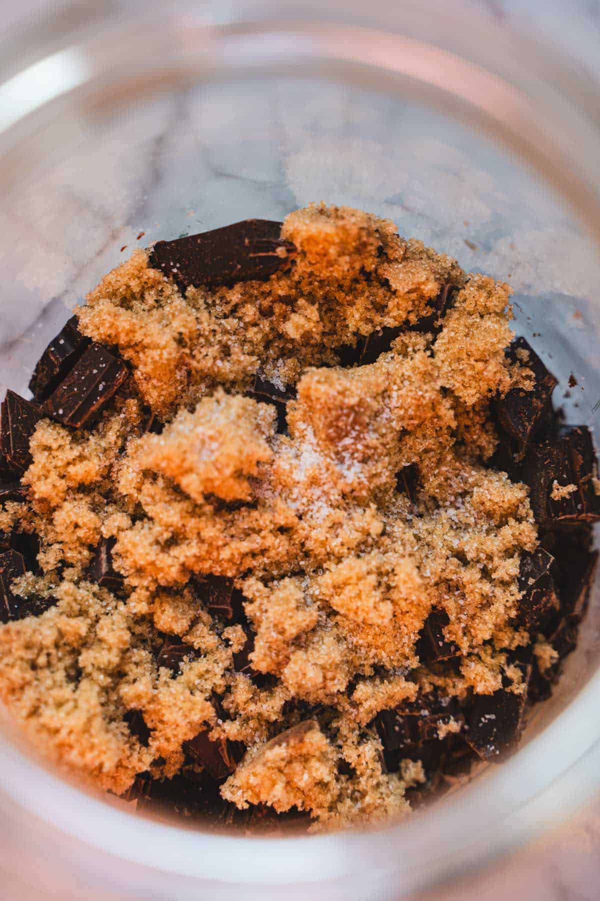 Brown sugar and salt layered on top of dark chocolate in a glass jar to make dark hot chocolate mix.