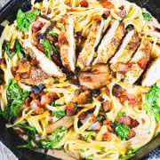 Chicken Marsala Fettuccine in a black cast iron skillet garnished with crispy pancetta and fried sage.