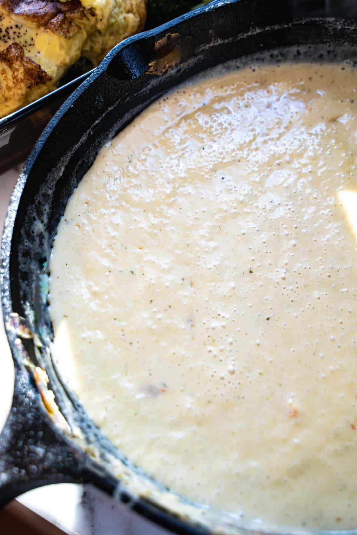 Whipped egg mixture in a black cast iron skillet cooking until set for cottage cheese egg casserole.
