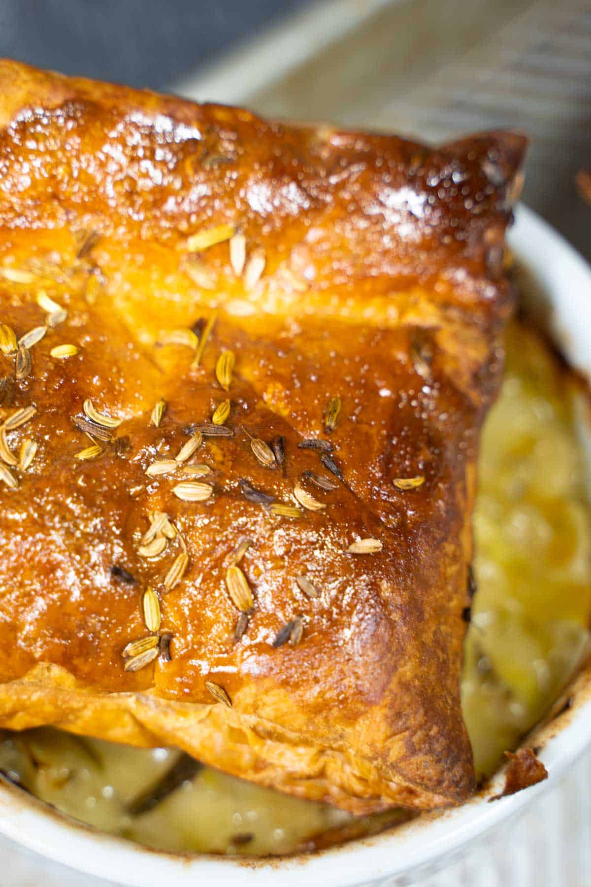Baked puff pastry pot pie top crust placed gently over hot ramekin filling for a individual puff pastry chicken pot pie.