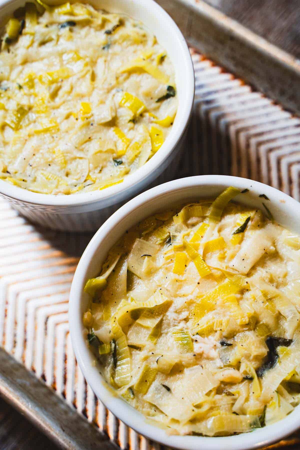 creamy leek pot pie filling ladled over the chopped rotisserie chicken in individual ramekins to make puff pastry chicken pot pie.