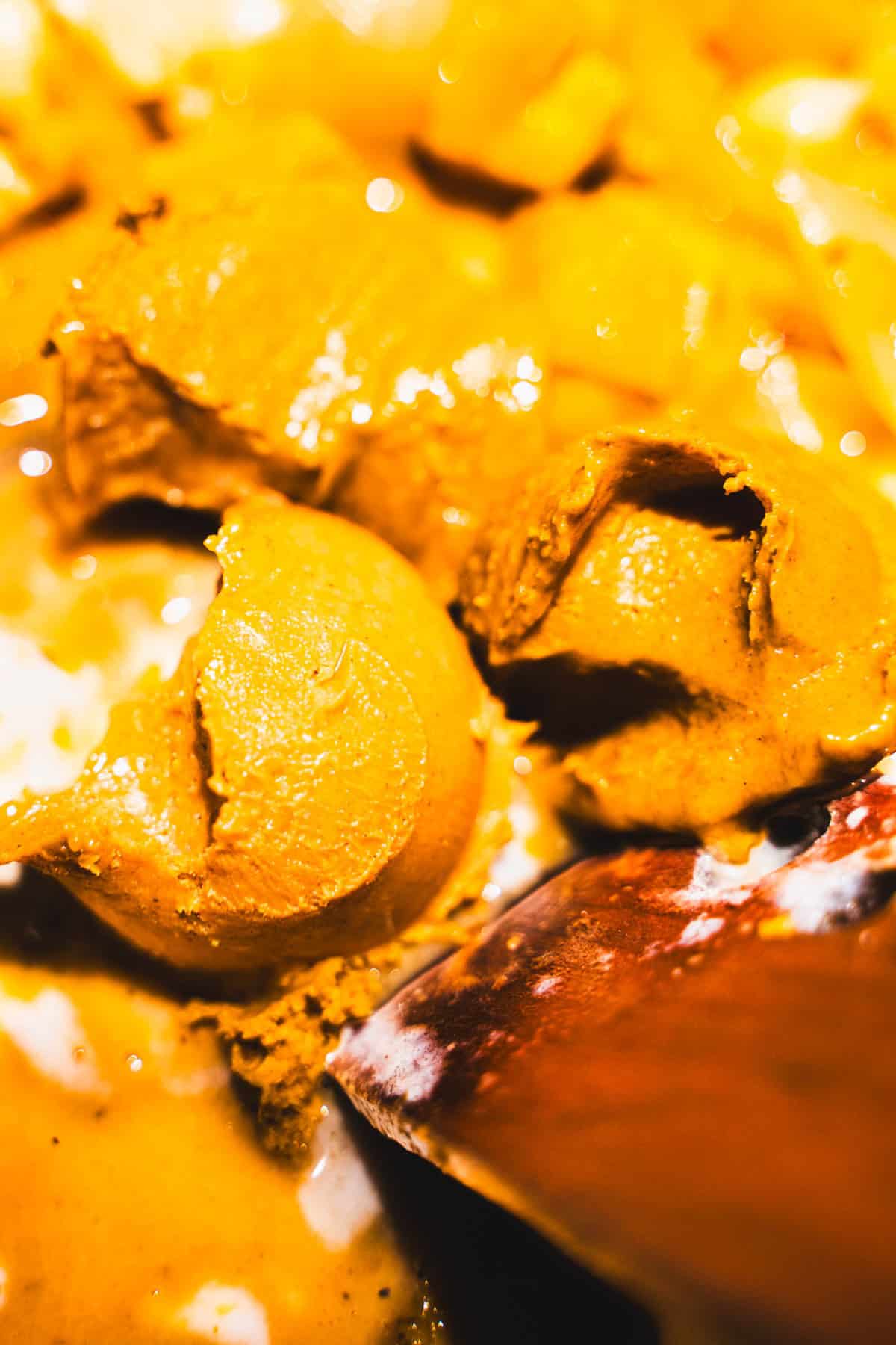 Adding peanut butter to sweet potatoes and onions in a soup pot for peanut butter and sweet potato coconut milk soup.