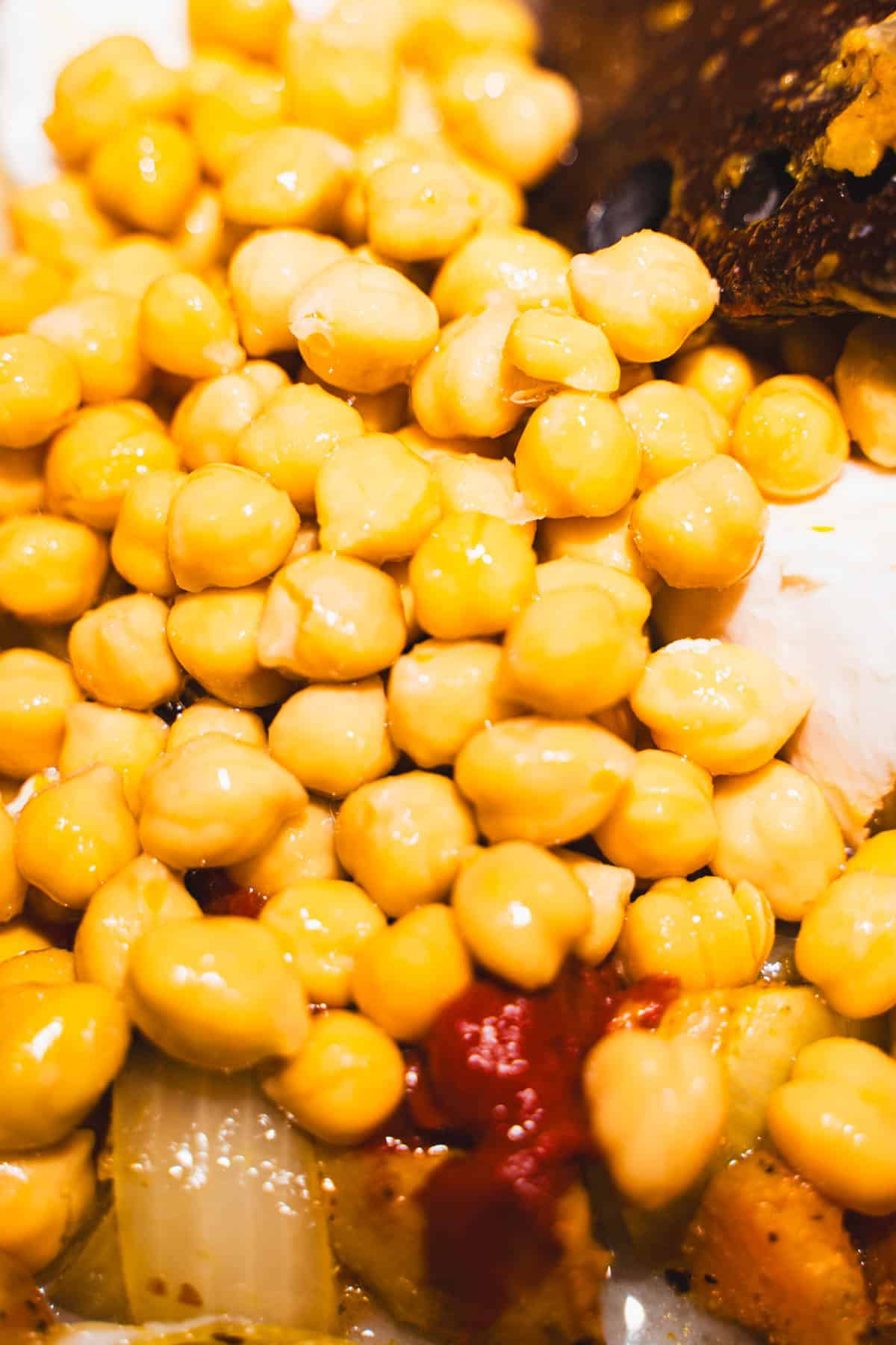 Chick peas and tomato paste in soup pot with roasted sweet potatoes and caramelized shallots.