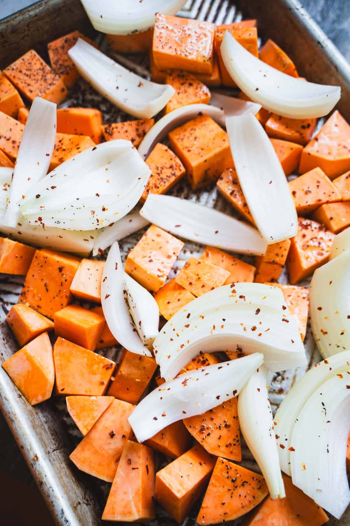 Cubed sweet potatoes and shallots thinly sliced tossed on a baking sheet with oil, salt and pepper.