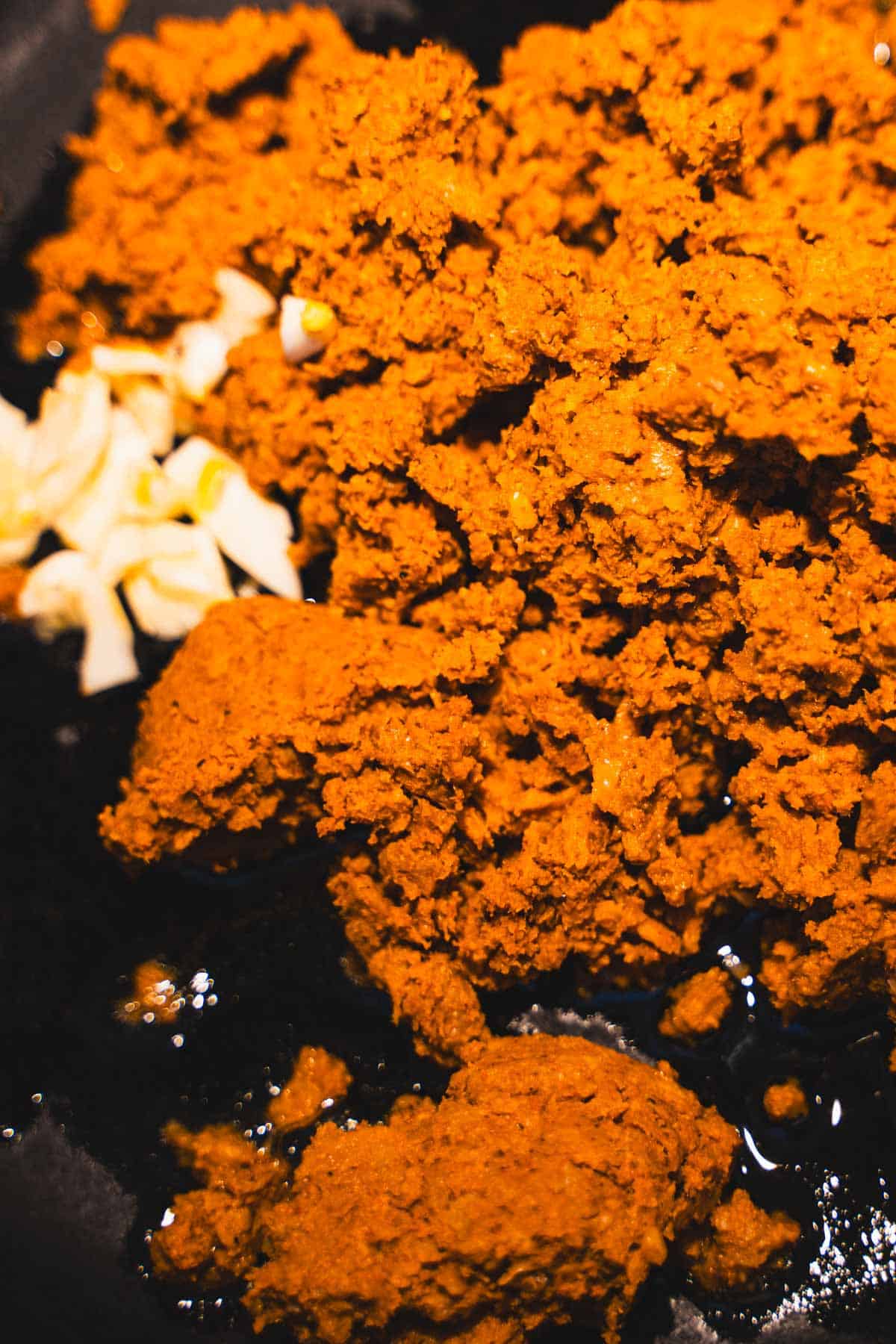 Plant based chorizo and garlic in a black cast iron skillet for Spanish eggs with plant based chorizo.