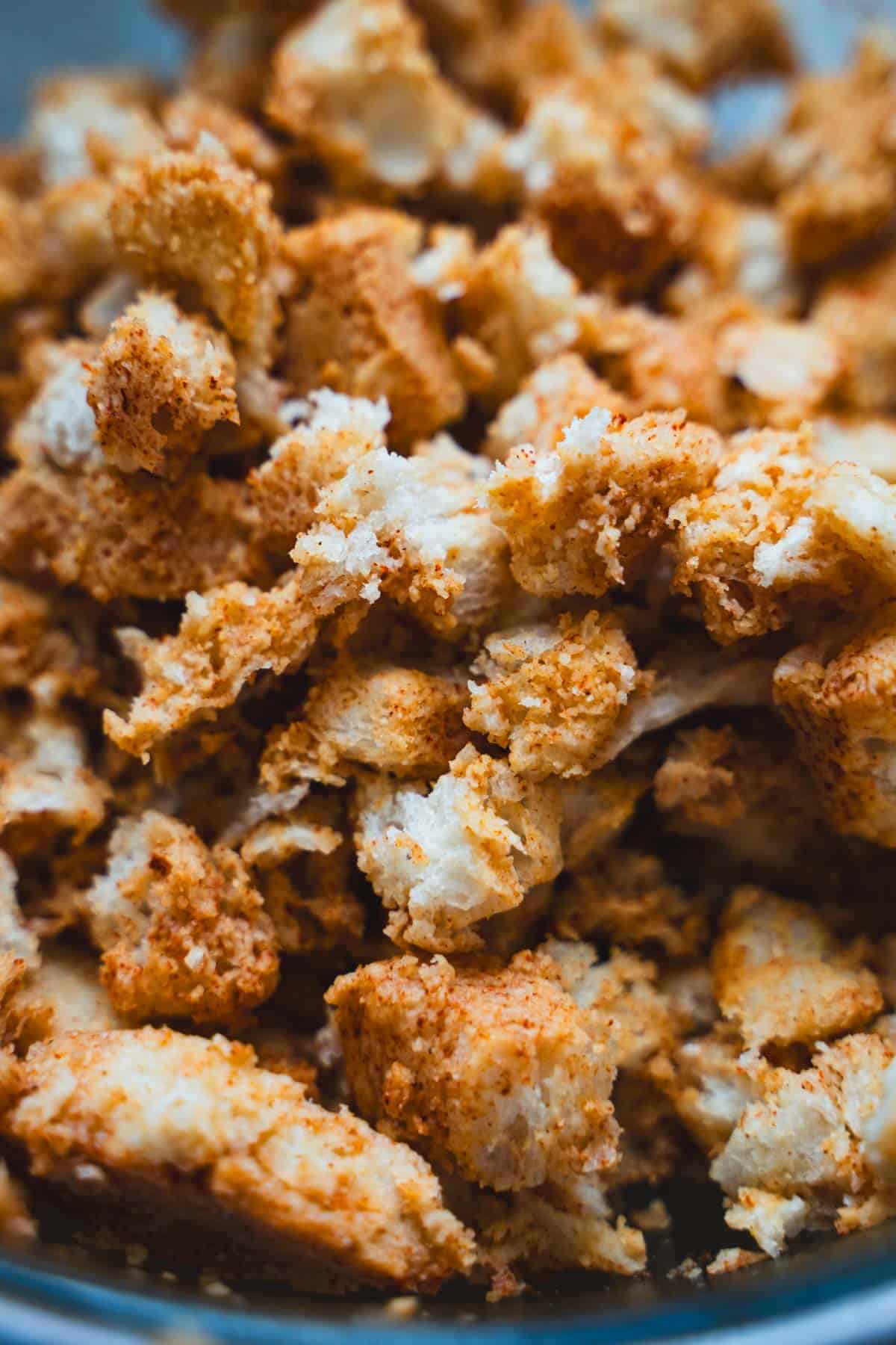 Paprika softened bread cubes for Spanish Migas for two in a large glass bowl.