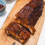 Fall off the bone sticky ribs on a cutting board with sides of coleslaw, bbq sauce and 2 cans of beer.