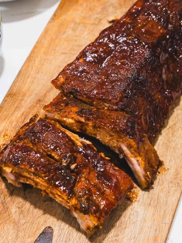 Fall off the bone sticky ribs on a cutting board with sides of coleslaw, bbq sauce and 2 cans of beer.