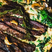 one skillet ribe eye steak dinner with steakhouse creamed spinach and mushrooms in a cast iron skillet.