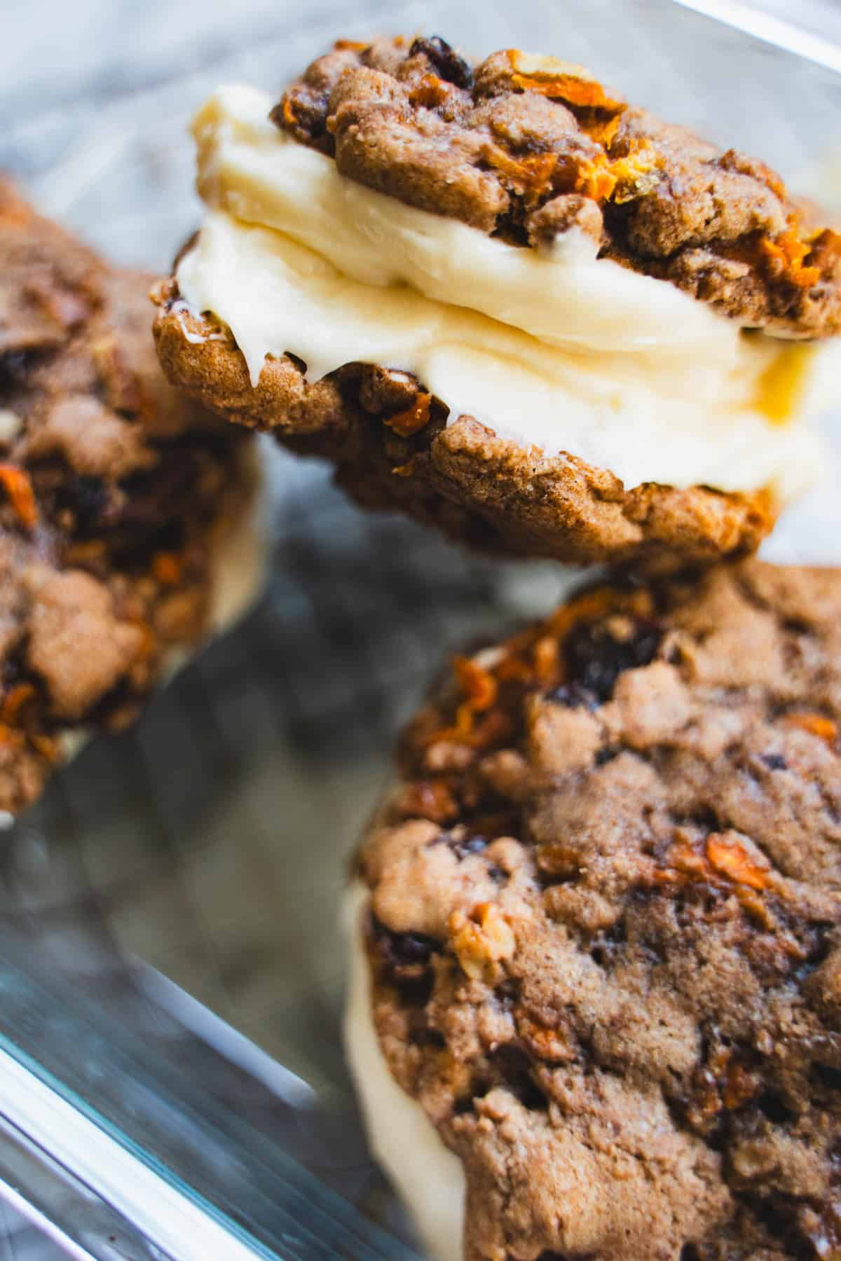 3 carrot cake sandwich cookies piled on top of each other in a glass container.