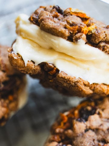 3 carrot cake sandwich cookies piled on top of each other in a glass container.