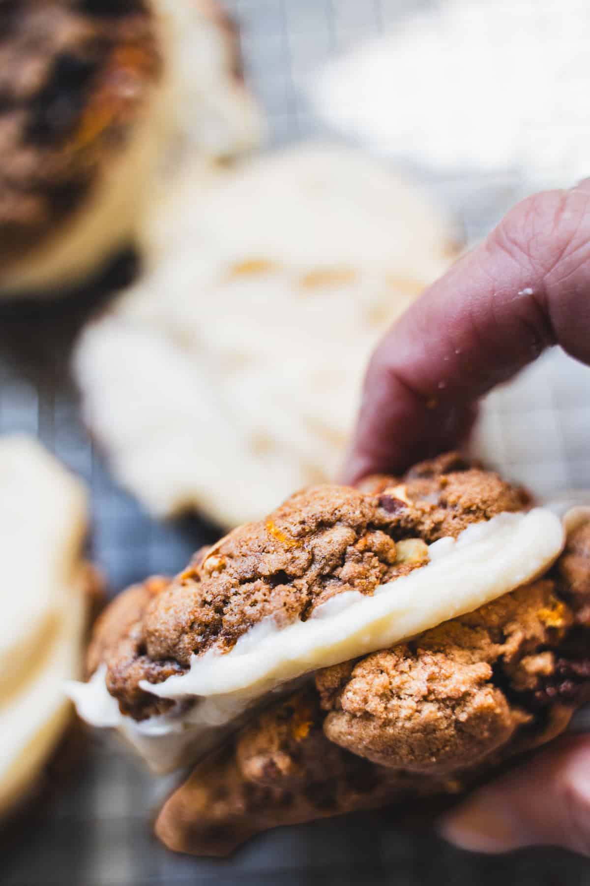 Carrot cake cookie sandwich held in a hand.