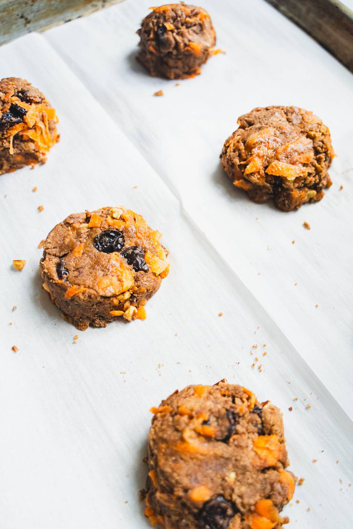 Carrot cake cookie batter in 2 inch rounds on parchment lined baking sheet.