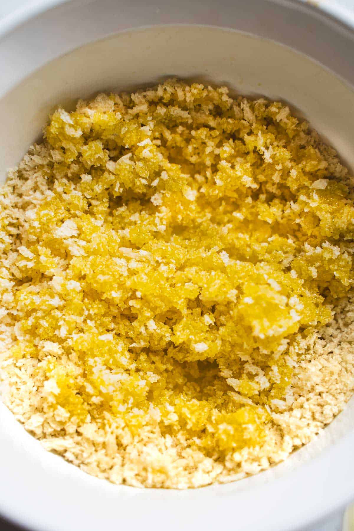 Panko and olive oil in white microwave safe bowl to make a toasted panko topping.