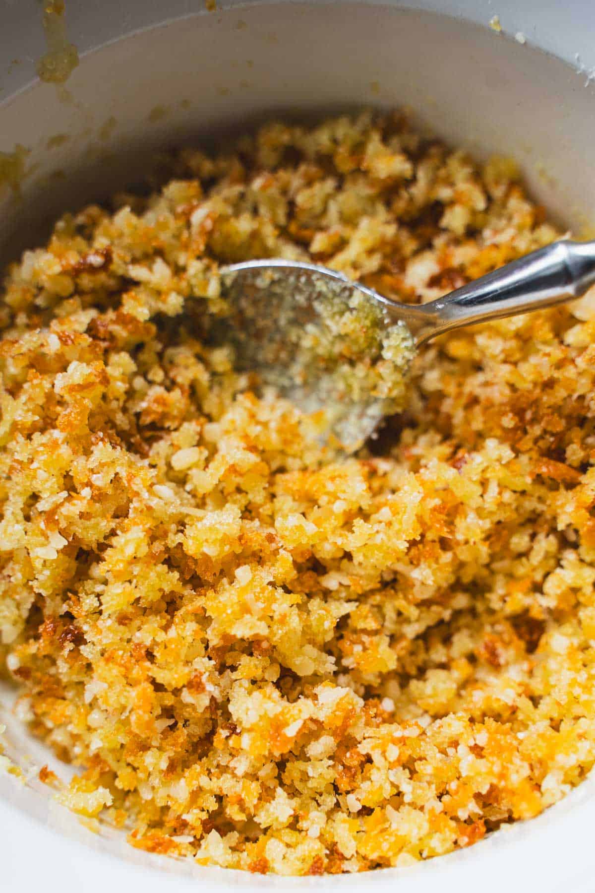 Toasted panko topping for 3 cheese mac and cheese with a teaspoon in a white ramakin.