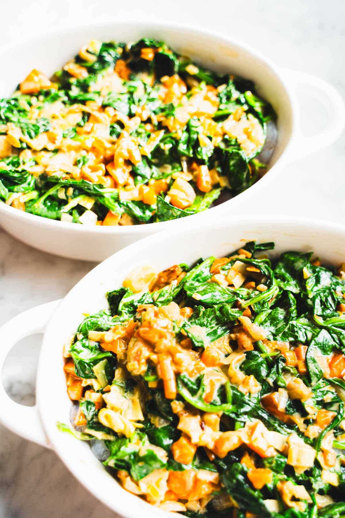 Vegetable sauce layered on top of seafood in white ramekin for seafood pot pie.