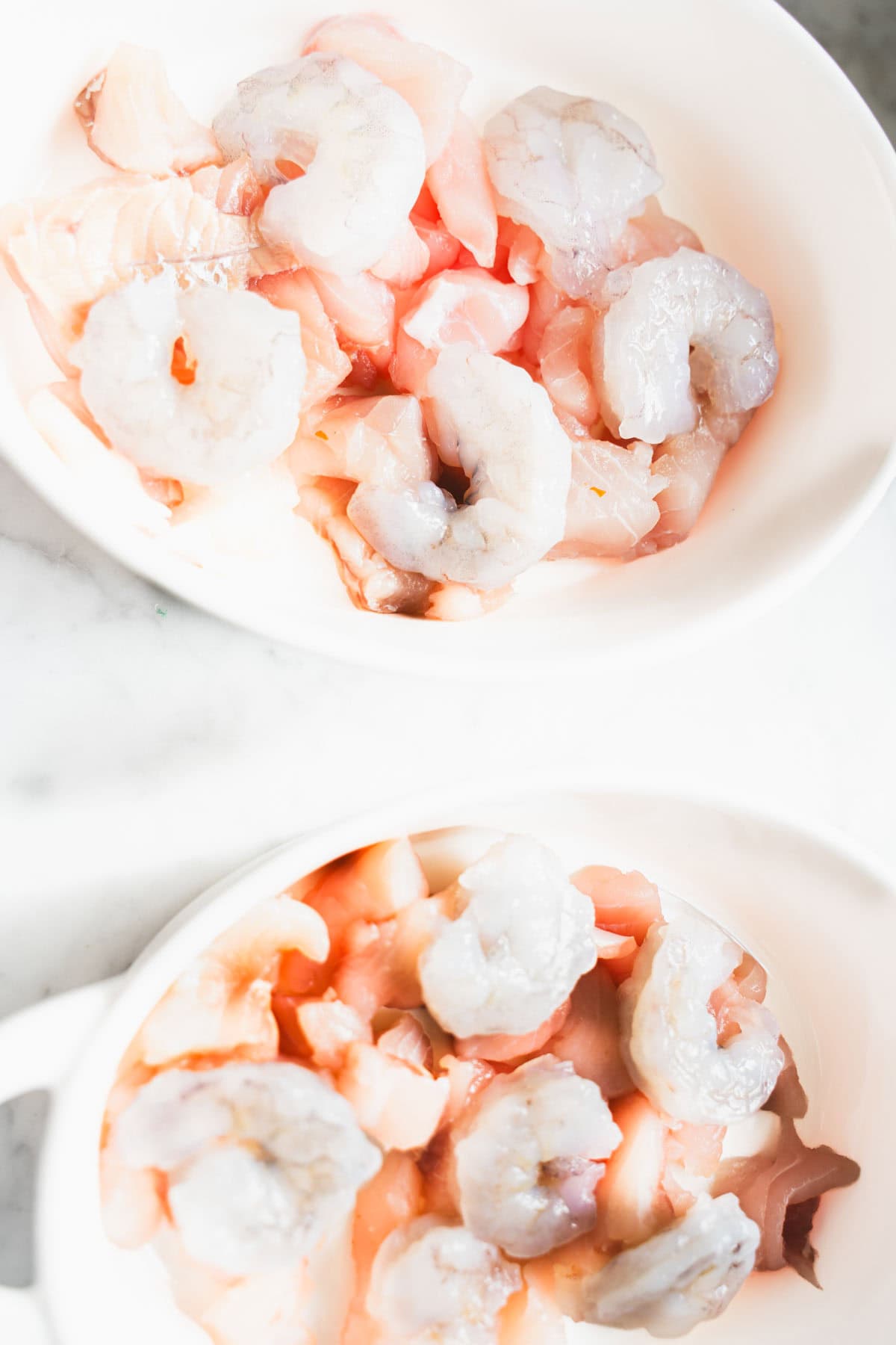 Whitefish and shrimp layed on the bottom of a white ramekin for Fisherman's Pie