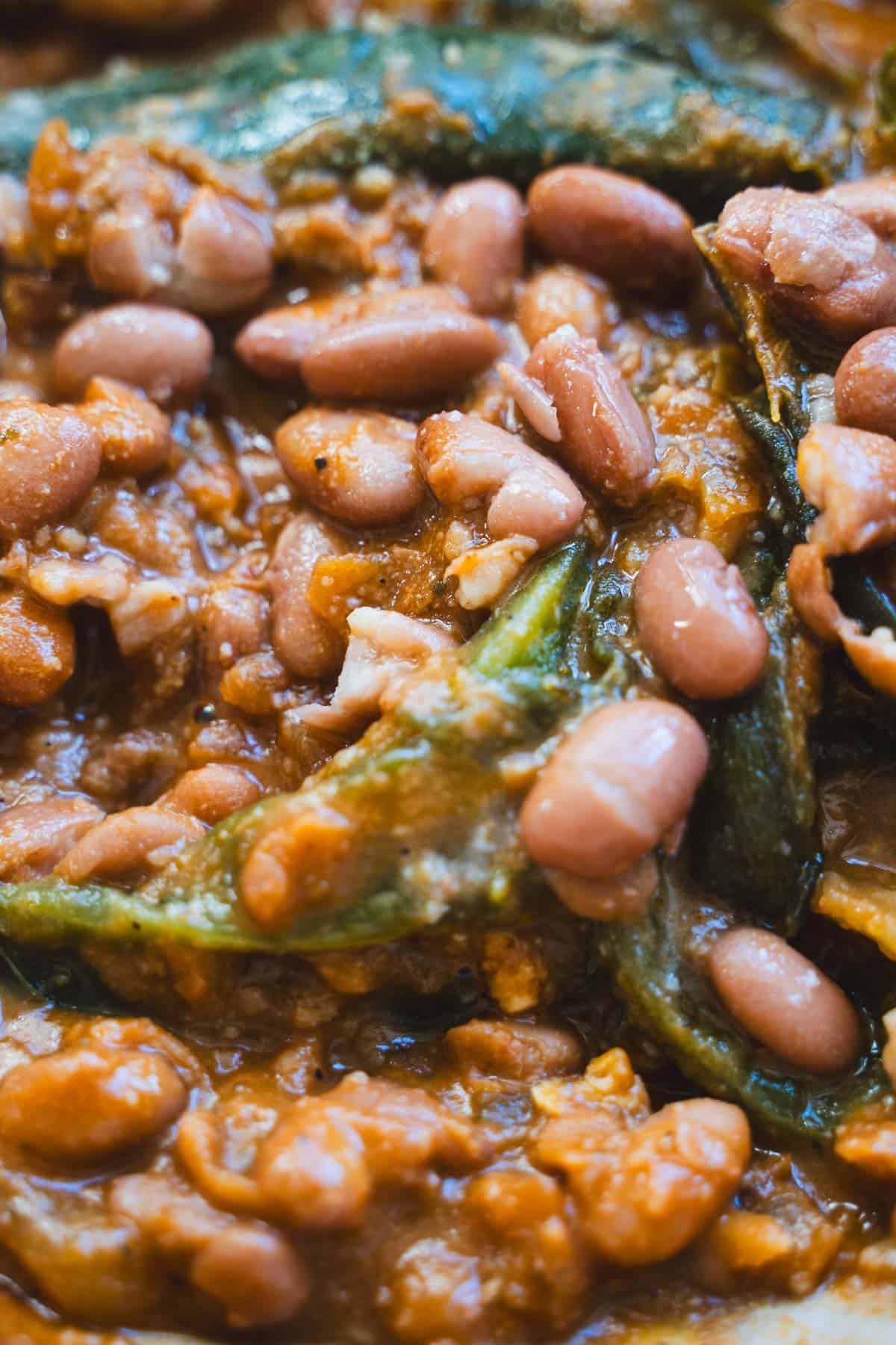 whole and mashed pinto beans with chile relleno pepper in a dutch oven.
