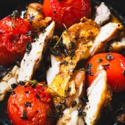Pan fried chicken and pan fried tomatoes in a cast iron skillet sprinkled with crispy oregano.