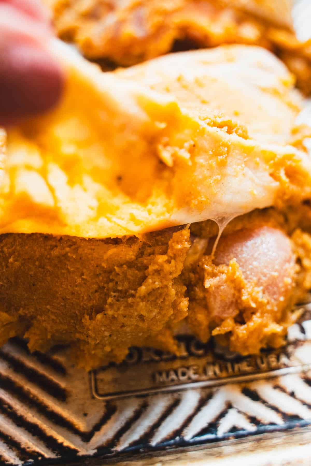 Fingers lifting skin to work miso paste under the skin and all over the chicken thigh resting on a sheet pan.