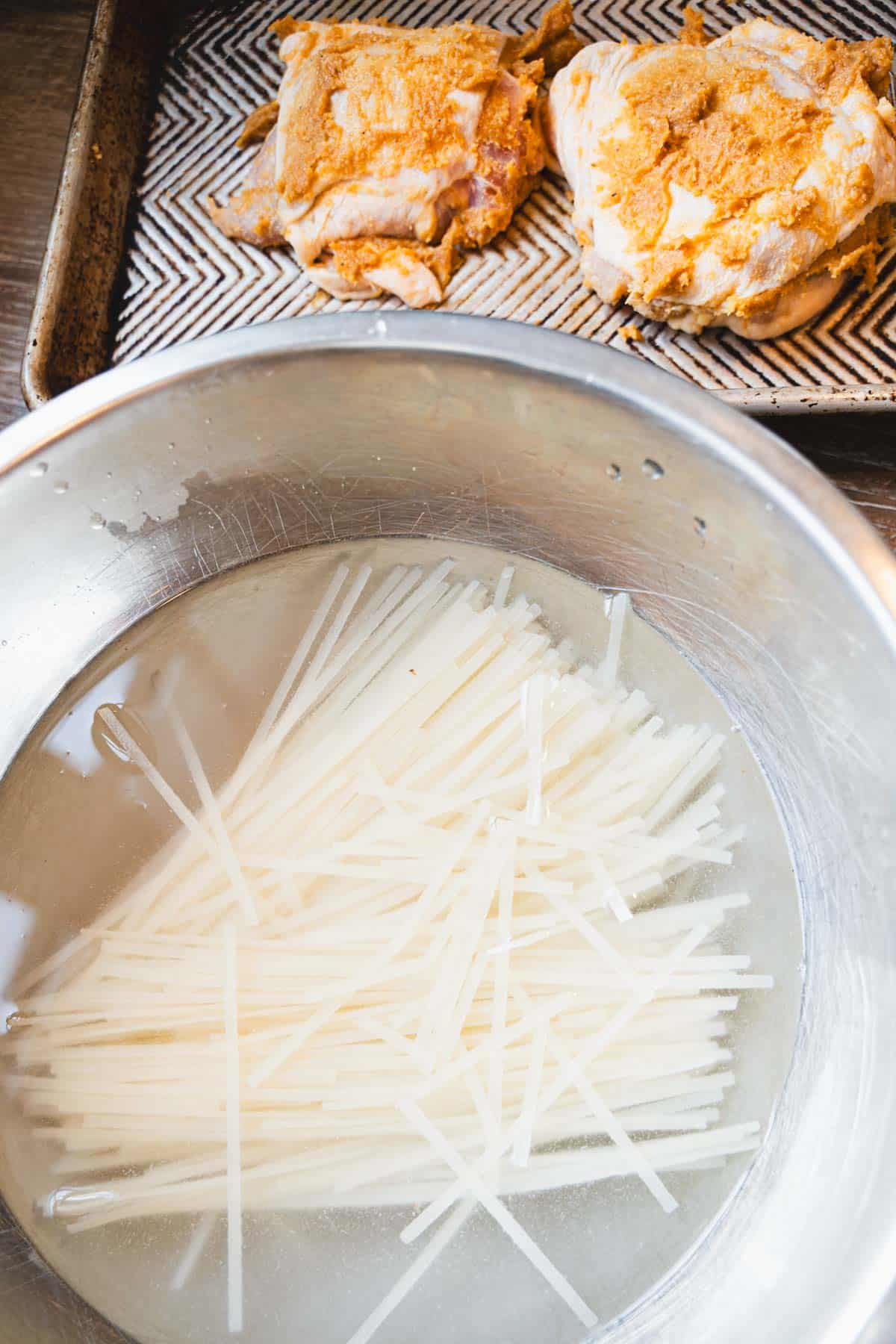 Rice noodles soaking in a mixing bowl to make pan fried glass noodle salad.